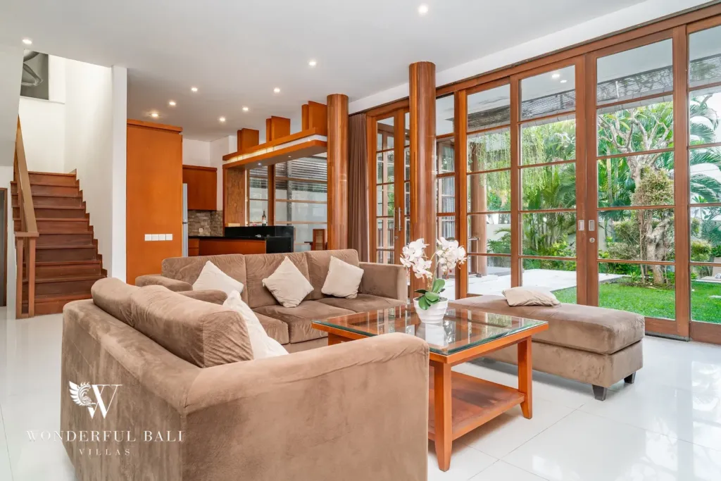 3BR villa for rent in Batu Belig, Seminyak — living room, sofas and a glass coffee table facing the garden windows