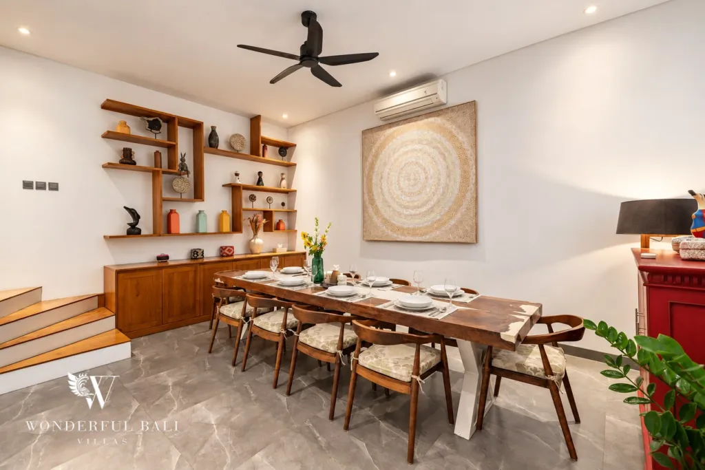 5BR villa for rent in Bumbak, Umalas — dining room, dining table beside built-in timber shelving and a red console