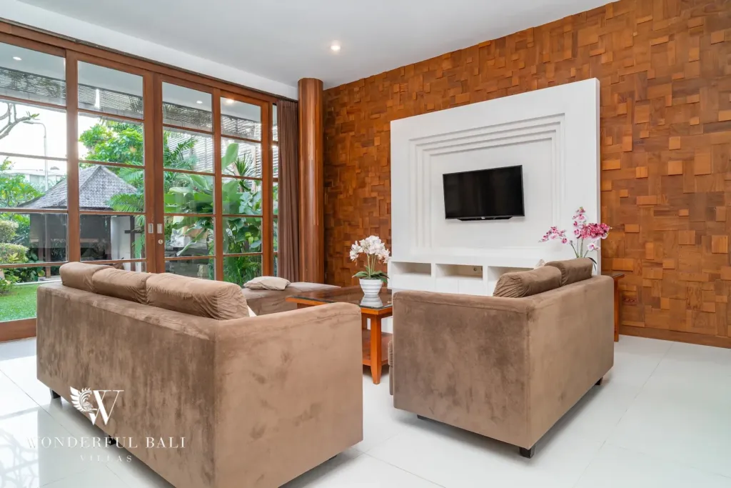 3BR villa for rent in Batu Belig, Seminyak — living room, seating area with a wall-mounted TV set into a teak parquet wall