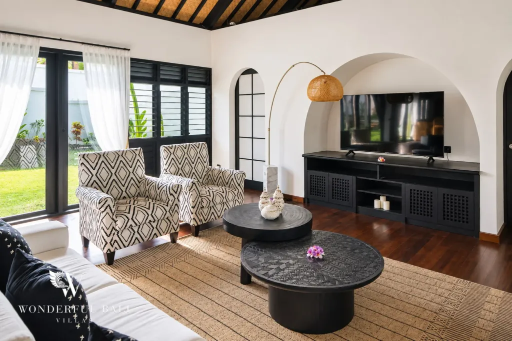 5BR villa for rent in Munggu, Bali — living room, seating area with patterned armchairs and a wall-mounted TV