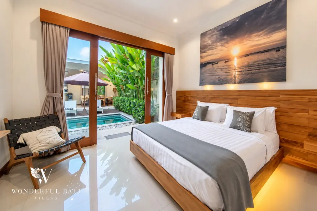 4BR villa for rent in Umalas, Bali — bedroom, teak headboard wall, sliding doors onto the pool