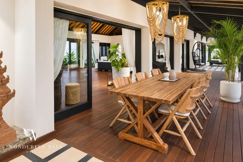 5BR villa for rent in Munggu, Bali — dining area, teak dining table under woven pendant lights beside the living room