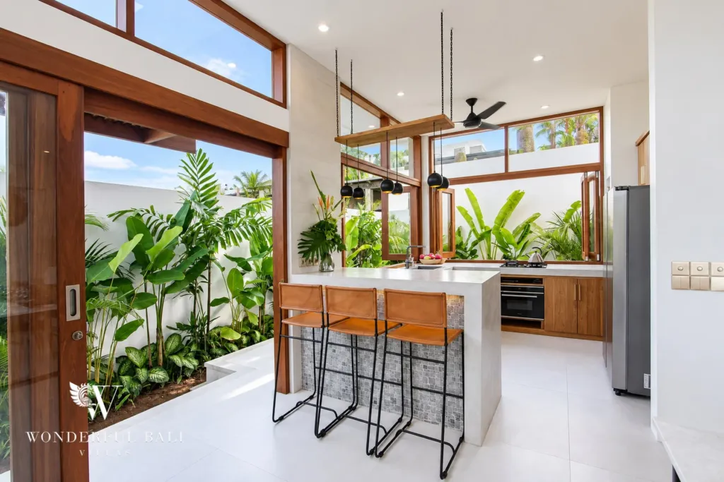 4BR villa for rent in Cemagi — kitchen, island with bar stools beside a planted courtyard