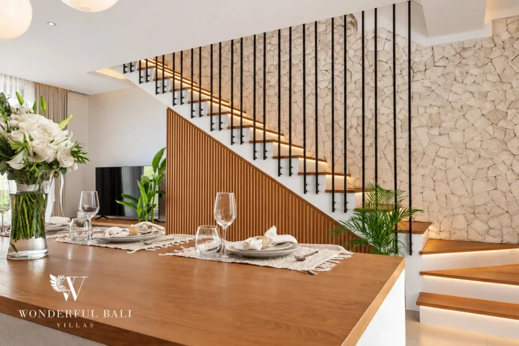 2BR villa for rent in Padonan, Canggu — dining, dining table beside a timber-slatted staircase and stone wall