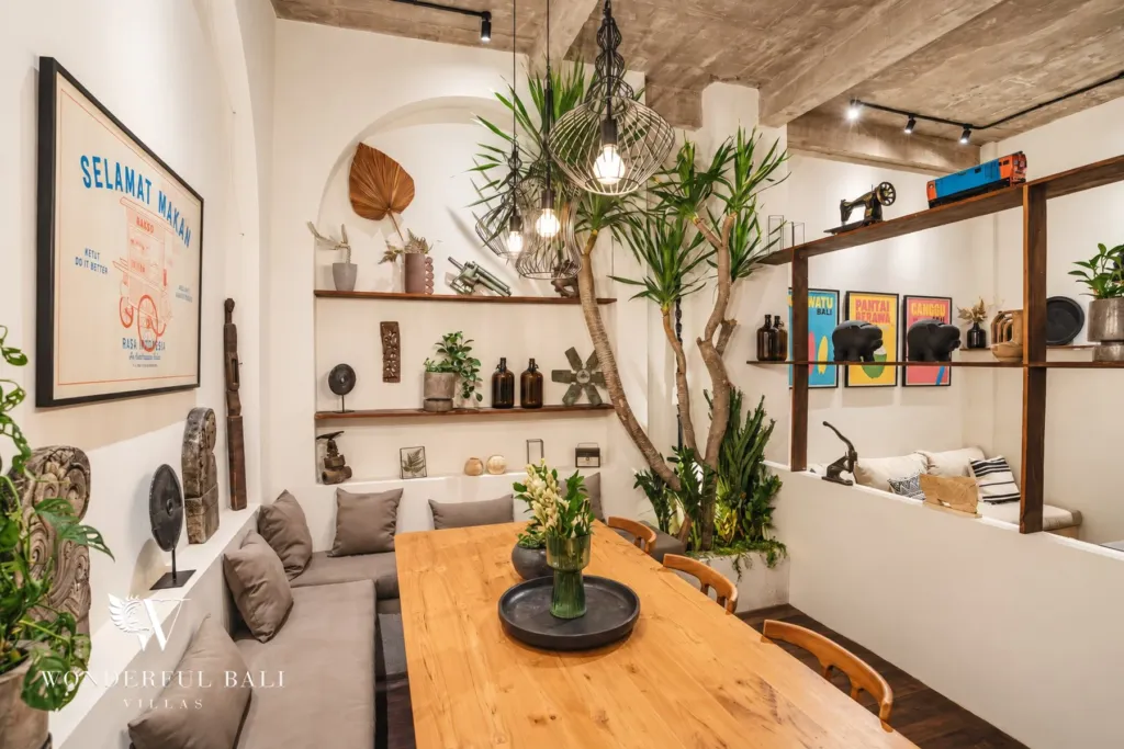 2BR villa for rent in Berawa, Canggu — dining area, teak dining table beside the framed poster wall and open shelving