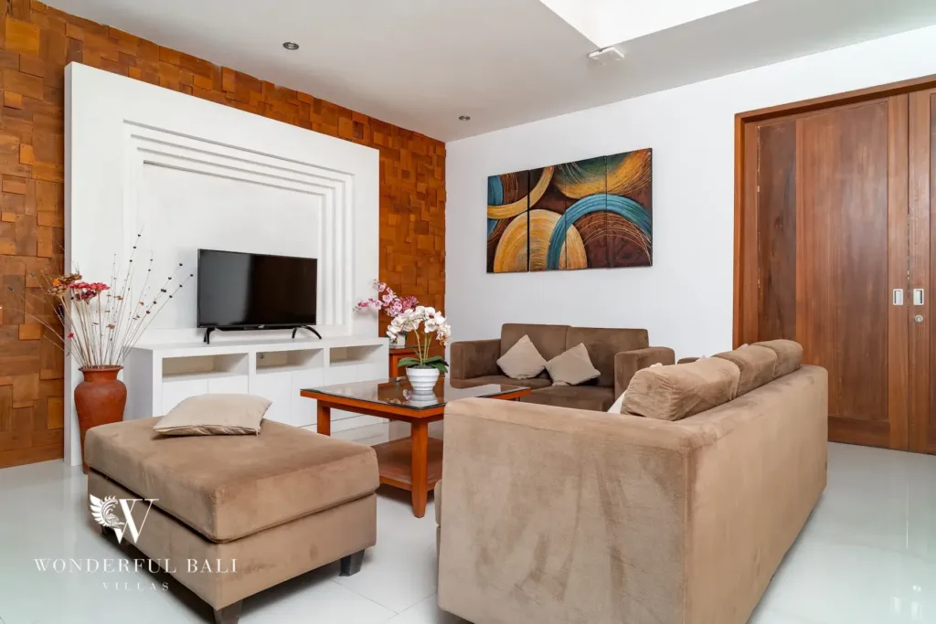 3BR villa for rent in Batu Belig, Seminyak — second lounge, sofas and ottoman beside a teak parquet feature wall