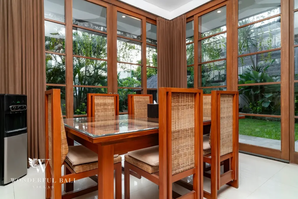 3BR villa for rent in Batu Belig, Seminyak — dining room, glass-top teak dining table and rattan chairs facing the garden