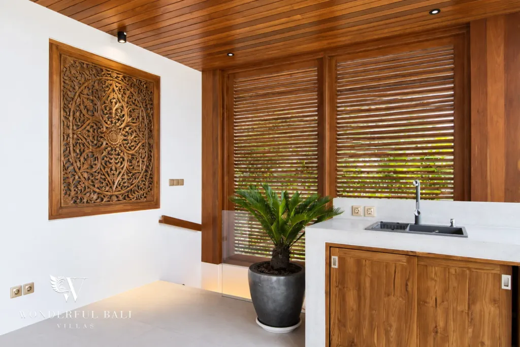 4BR villa for rent in Cemagi — kitchen, sink counter with teak cabinets and carved wall panel