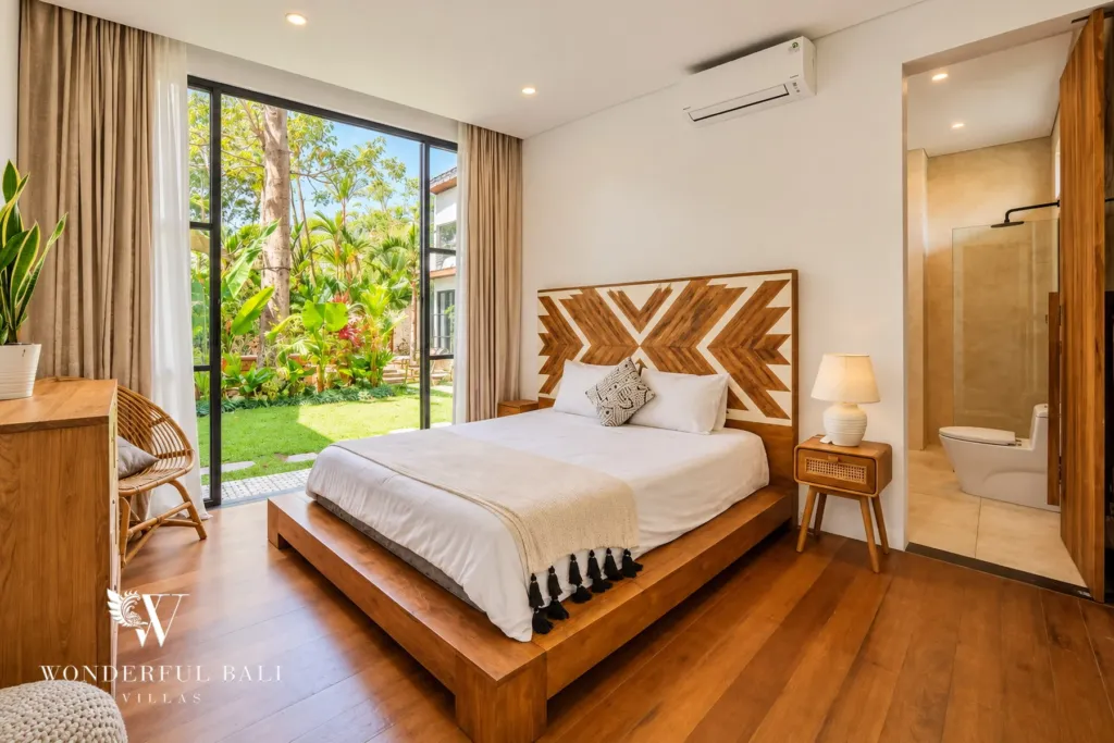 5BR villa for rent in Seseh, Bali — bedroom, bed with a carved timber headboard facing the garden doors