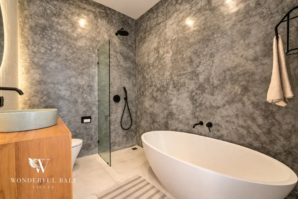 5BR villa for rent in Seseh, Bali — bathroom, micro-cement bathroom with a black stone tub and walk-in shower