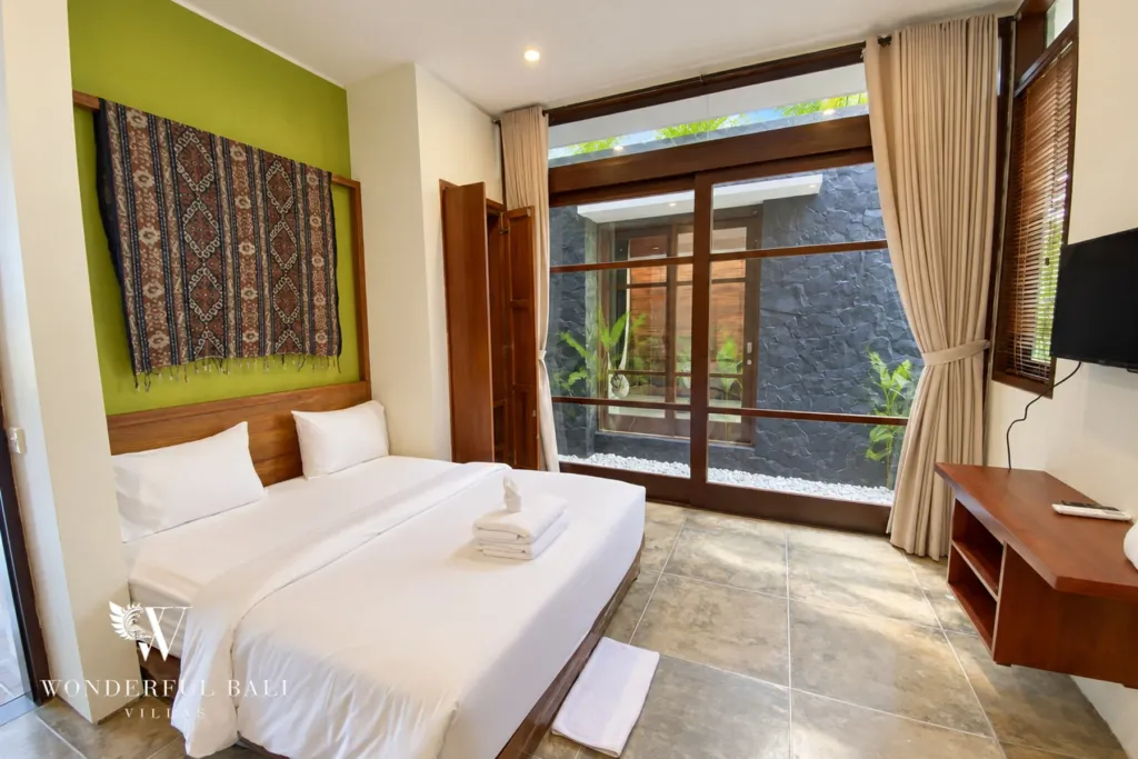 3BR villa for sale in Jimbaran — bedroom, bedroom with an ikat wall hanging and doors to a stone courtyard