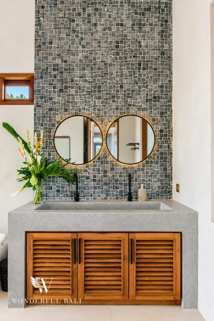4BR villa for rent in Cemagi — bathroom, concrete vanity with twin round mirrors and stone mosaic