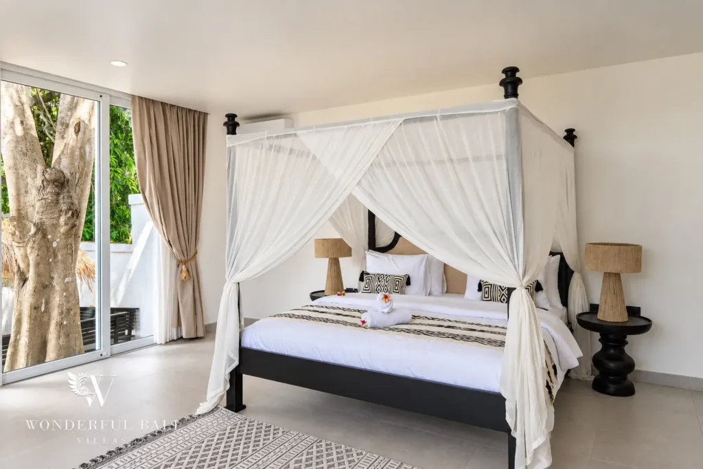 5BR villa for rent in Munggu, Bali — bedroom, canopy bed facing the garden through full-height glass