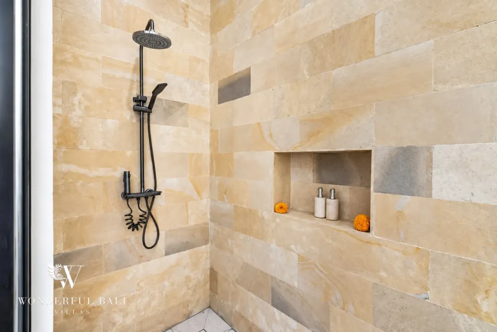 3BR villa for rent in Umalas, Bali — bathroom, walk-in rain shower lined in warm sandstone with a recessed niche