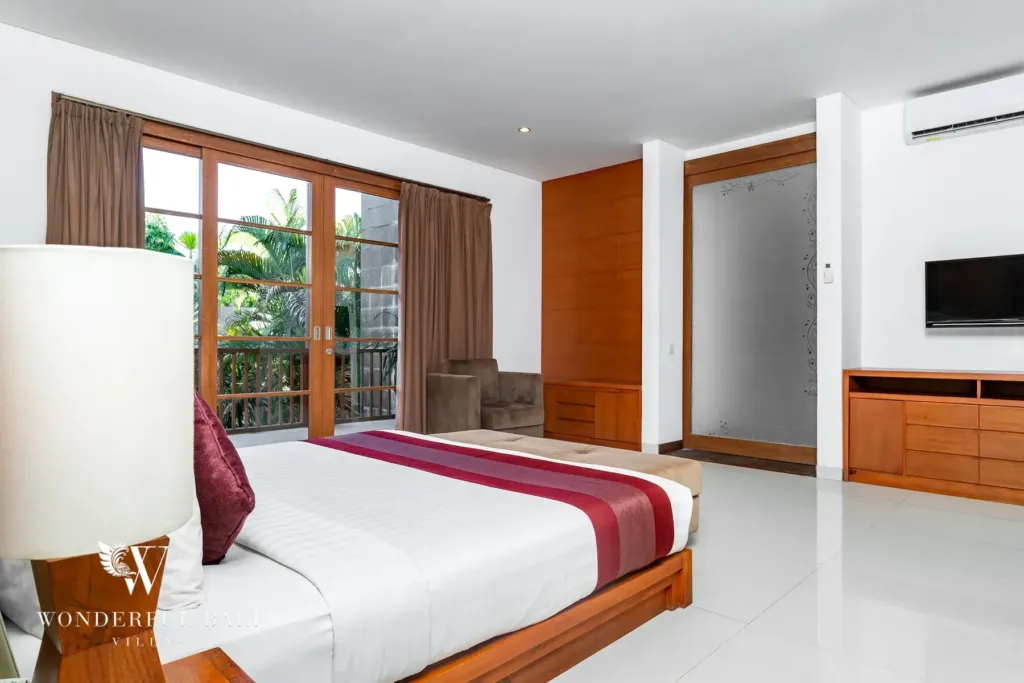 3BR villa for rent in Batu Belig, Seminyak — bedroom, bedside lamp and timber side table beside the king bed