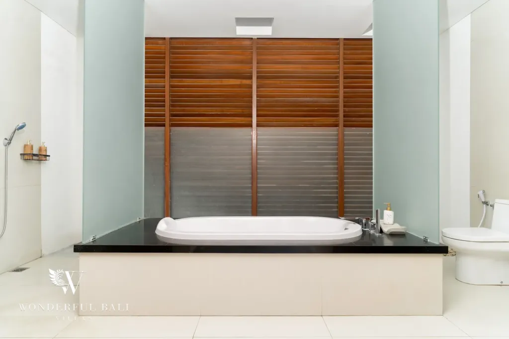 3BR villa for rent in Batu Belig, Seminyak — bathroom, set-in bathtub on black granite behind timber louvre shutters