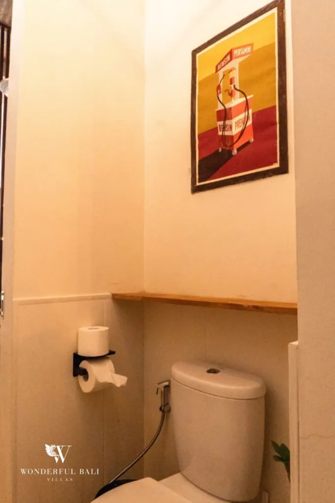 2BR villa for rent in Berawa, Canggu — guest toilet, separate toilet with a timber shelf and a framed vintage poster