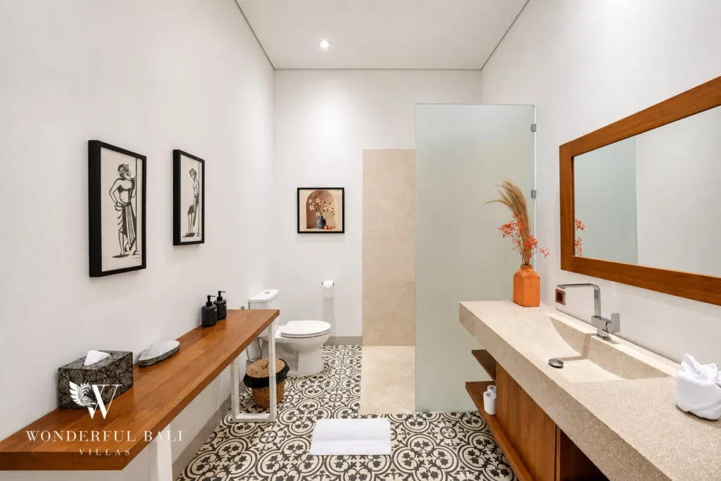 5BR villa for rent in Bumbak, Umalas — bathroom, long stone vanity with framed prints over monochrome floor tiles