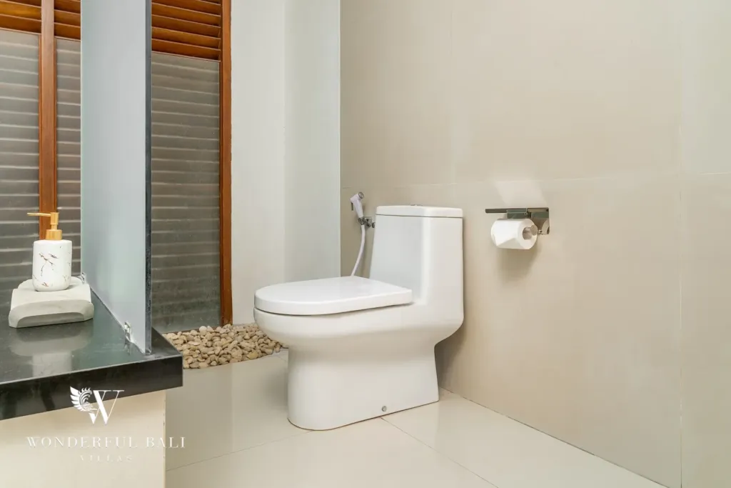 3BR villa for rent in Batu Belig, Seminyak — bathroom, separate toilet and pebble-set floor beside the shower screen