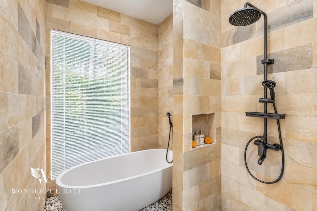 3BR villa for rent in Umalas, Bali — bathroom, freestanding tub and rain shower in warm sandstone