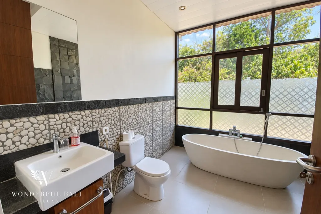 3BR villa for sale in Jimbaran — bathroom, ensuite with a freestanding bathtub and pebble-stone wall