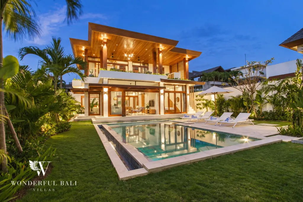 4BR villa for rent in Cemagi — exterior, lit villa, lawn and pool in the evening