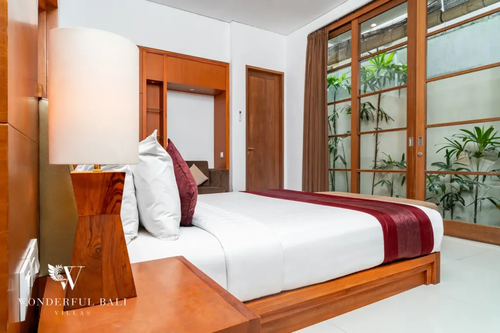 3BR villa for rent in Batu Belig, Seminyak — bedroom, king bed facing a glazed wall onto a planted light well