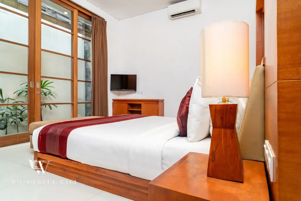 3BR villa for rent in Batu Belig, Seminyak — bedroom, glazed corner onto the planted light well beside the bed