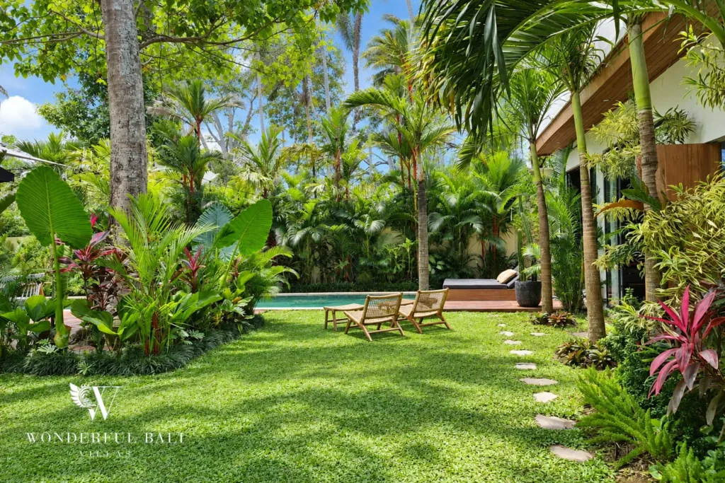 5BR villa for rent in Seseh, Bali — garden, lawn framed by heliconia and palms with the pool beyond