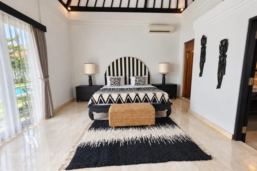 4BR villa for rent in Batu Bolong, Canggu — bedroom, front view of the bed with carved wall figures alongside