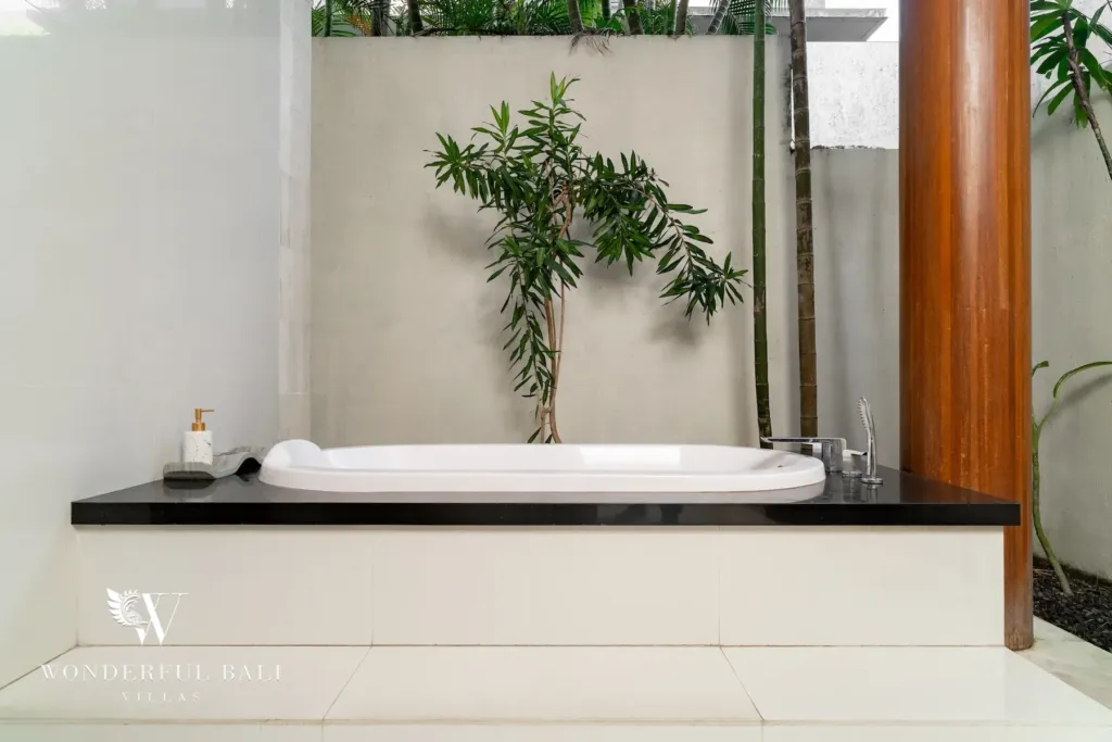 3BR villa for rent in Batu Belig, Seminyak — bathroom, bathtub open to a small planted courtyard with a slender tree