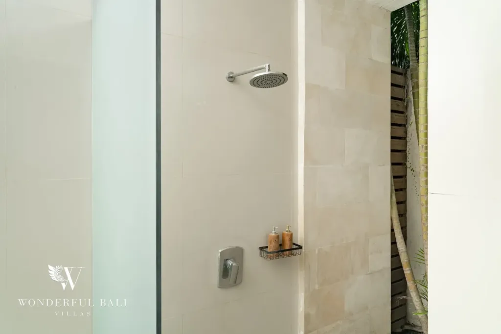 3BR villa for rent in Batu Belig, Seminyak — bathroom, glass-screened rain shower beside a planted stone wall