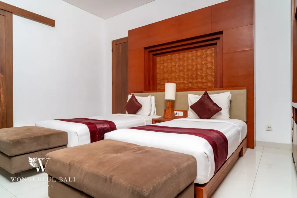 3BR villa for rent in Batu Belig, Seminyak — bedroom, wide view of the twin room with a carved headboard panel