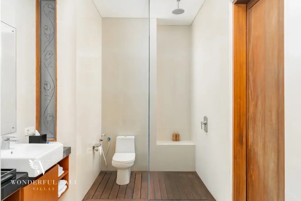 3BR villa for rent in Batu Belig, Seminyak — bathroom, walk-in rain shower on a timber deck with a carved stone panel
