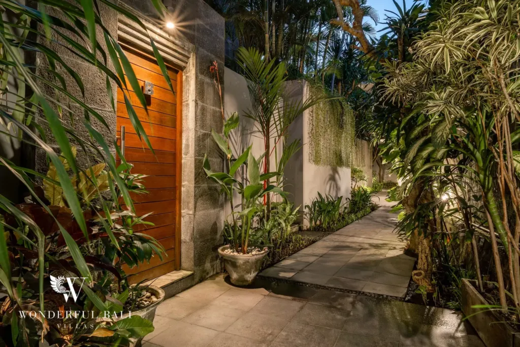 3BR villa for rent in Batu Belig, Seminyak — entrance, timber entrance door set into a stone wall along the planted path