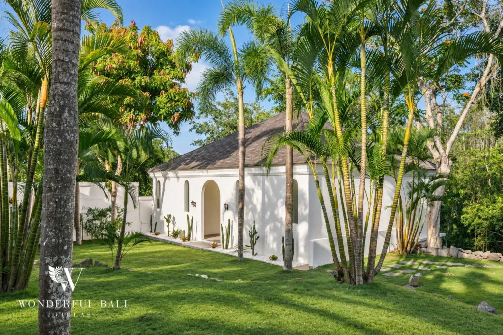 5BR villa for rent in Munggu, Bali — exterior, the villa seen from the far lawn through palms and bamboo