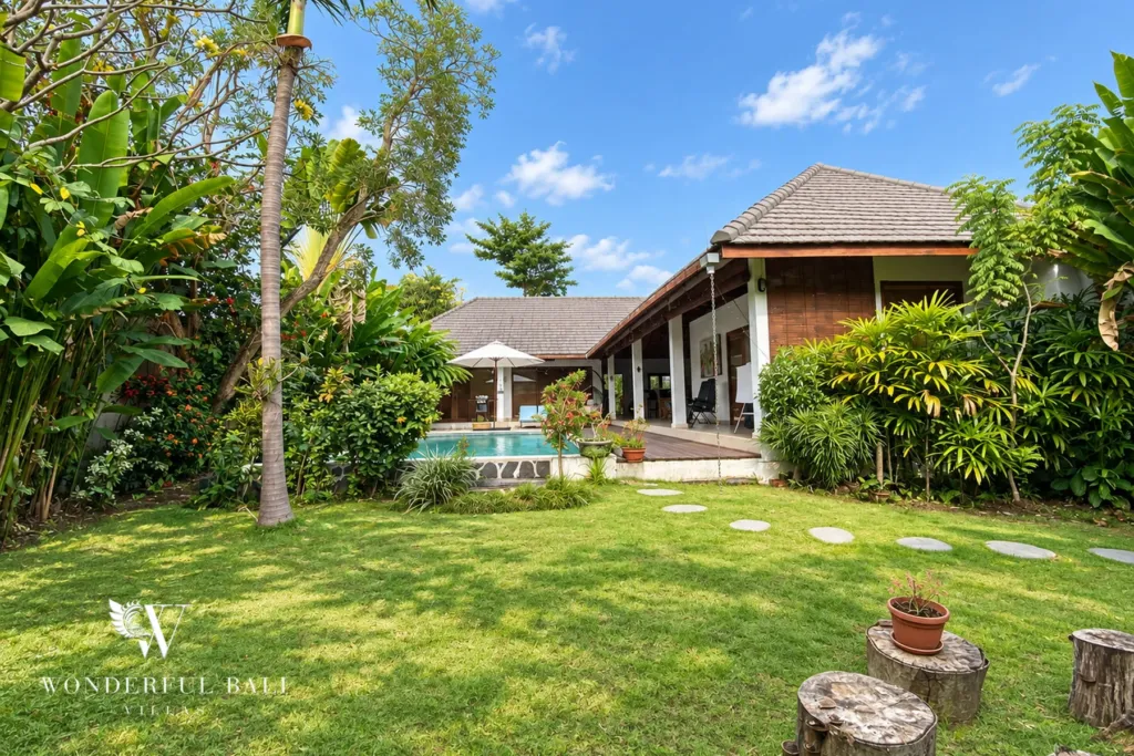 3BR villa for rent in Padonan, Canggu — garden, open lawn with frangipani trees and stepping stones to the villa