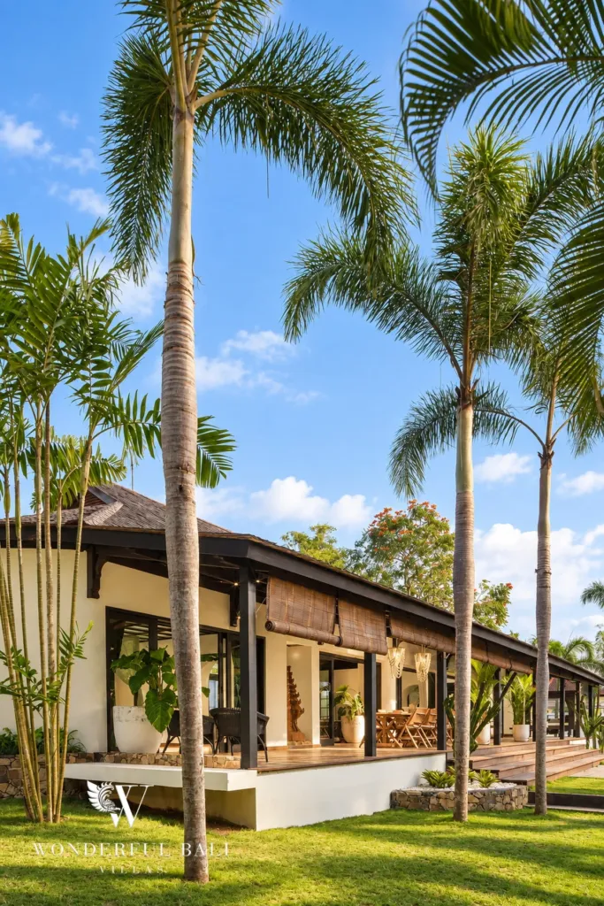 5BR villa for rent in Munggu, Bali — exterior, royal palms framing the long pavilion and its thatched roof