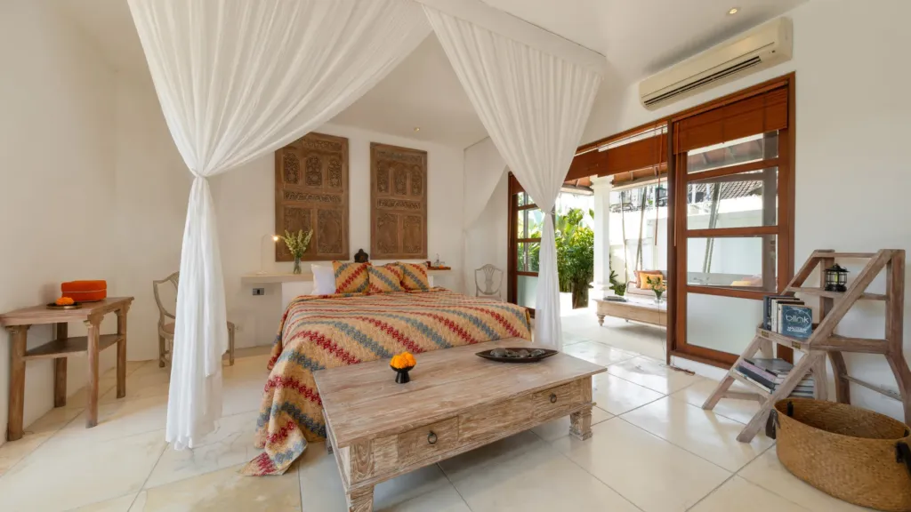 Canopy bedroom with a carved antique headboard at Villa V Seminyak