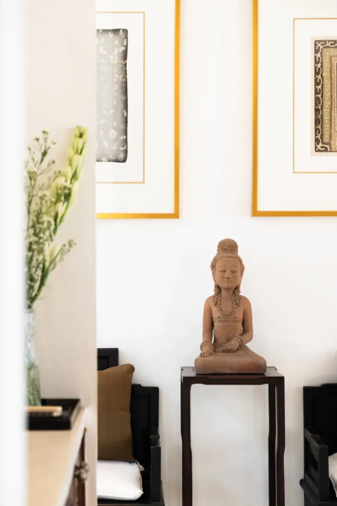 Carved Buddha figure and framed art in the living pavilion at Villa V Seminyak