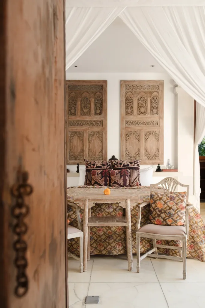 Dining table beside tall carved teak doors at Villa V Seminyak