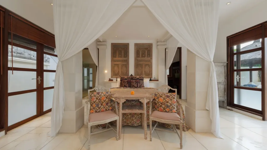 Bedroom with a timber table and carved panel headboard at Villa V Seminyak