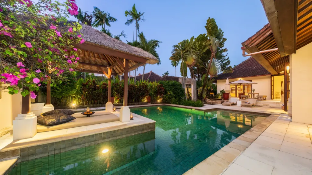 Pool and thatched pavilions lit at dusk at Villa V Seminyak