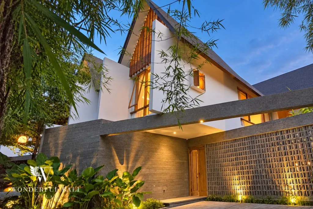 2BR villa long term rental Pererenan — villa entrance with timber screens and stone walls lit at dusk