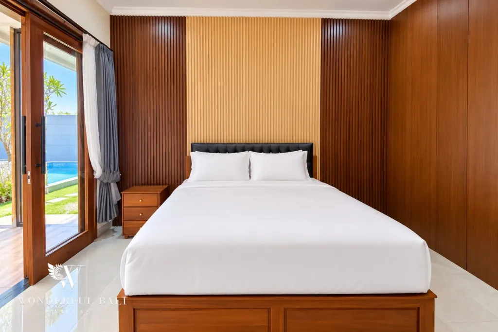 3BR villa for sale or rent in Sanur — bedroom with timber-panelled wall and glass door to the pool