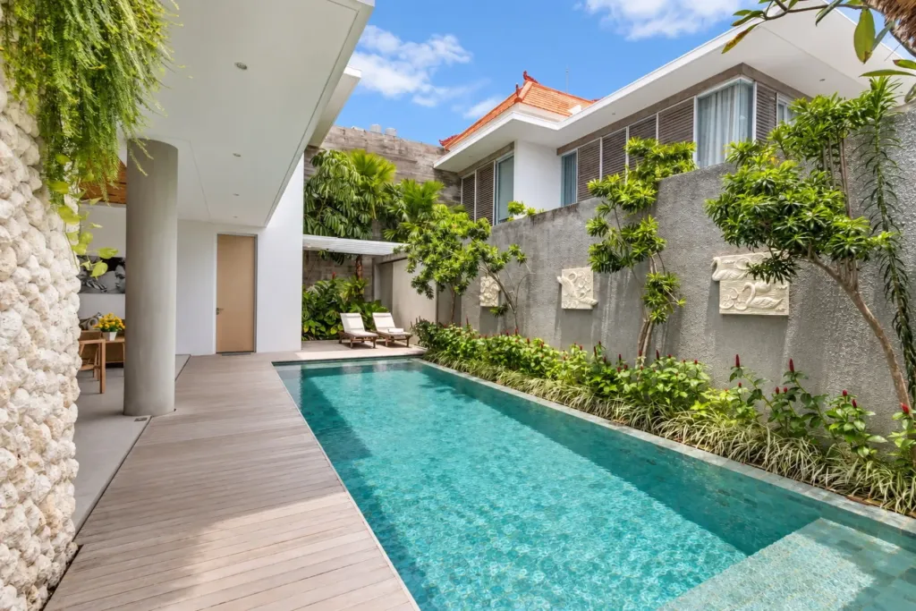 Villa Swan 02 — pool, running beside a planted wall with sun loungers on the timber deck