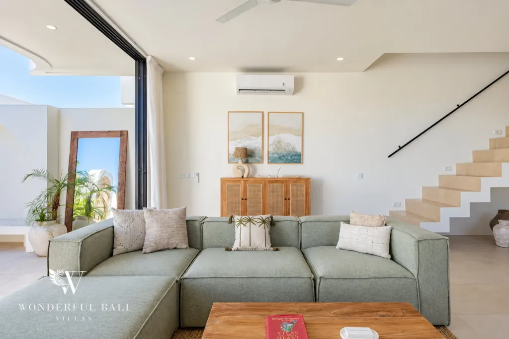 2BR villa for rent in Munggu — sage green sofa beside floor-to-ceiling glass