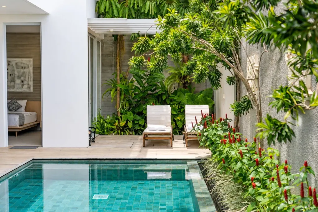 Villa Swan 02 — pool, sun lounger on the terrace beside frangipani and red heliconia planting