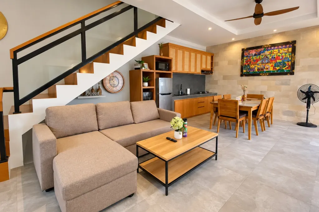 3BR villa for rent in Sanur — open-plan living room with corner sofa, staircase and kitchen beyond