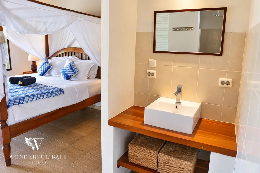 3BR villa for rent in Tabanan — four-poster bed with mosquito net beside a timber vanity